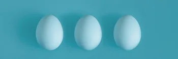 Three White chicken eggs on a blue background in the center.