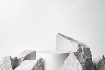 A minimalistic display featuring a smooth white cylinder surrounded by rough gray stone fragments 64 A minimalistic display featuring a smooth white cylinder surrounded by rough gray stone fragments