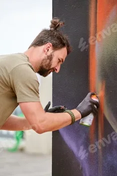 Attractive male artist is painting picture with paint spray can spraying it onto canvas 5 Attractive male artist is painting picture with paint spray can spraying it onto canvas
