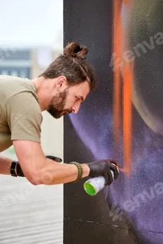 Attractive male artist is painting picture with paint spray can spraying it onto canvas 3 Attractive male artist is painting picture with paint spray can spraying it onto canvas