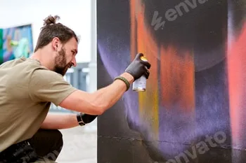 Attractive male artist is painting picture with paint spray can spraying it onto canvas 3 Attractive male artist is painting picture with paint spray can spraying it onto canvas