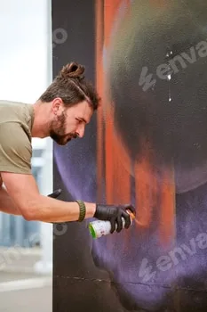 Attractive male artist is painting picture with paint spray can spraying it onto canvas 3 Attractive male artist is painting picture with paint spray can spraying it onto canvas