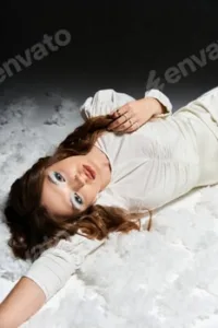 Elegant young woman lounging gracefully in a serene white setting during soft ambient light