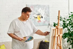 A queer artist passionately creating a unique masterpiece in a bright studio space