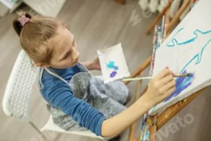 Concentrated Child Painting on Easel. Top view.