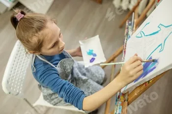 Concentrated Child Painting on Easel. Top view.