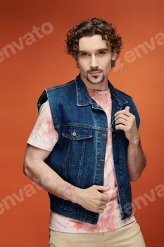 Handsome Emotional Man Posing Against a Vibrant Orange Backdrop