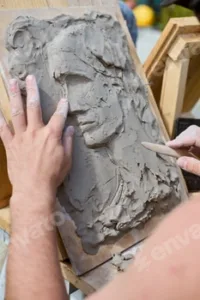 Creating clay relief portrait with wooden tools
