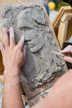 Creating clay relief portrait with wooden tools