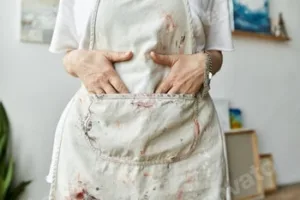 A mature artist in her paint-splattered apron enjoys creativity in her vibrant studio