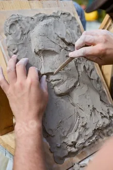 Creating clay relief portrait with wooden tools