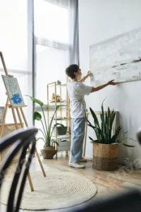 Mature woman arranging her artwork in a bright, inspiring art studio setting