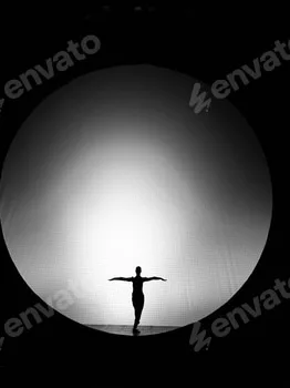 Silhouette of a dancer in front of circular light