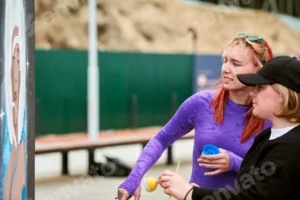 Two female artists painting picture with paint spray can spraying onto canvas at street exhibition