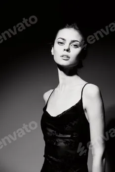 Elegant young woman in a black dress posing dramatically against a dark background, exuding