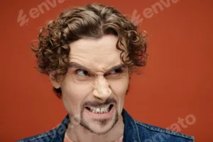 Handsome Emotional Man Expressing Feelings Against a Vibrant Orange Backdrop