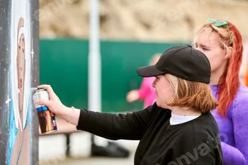 Two female artists painting picture with paint spray can spraying onto canvas at street exhibition 2 Two female artists painting picture with paint spray can spraying onto canvas at street exhibition