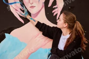 Young woman painting large art mural outdoors