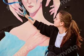 Young woman painting large art mural outdoors