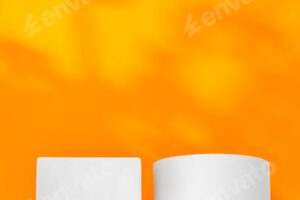 White geometric shapes on a vibrant orange background with soft shadows in a well-lit indoor setting